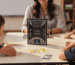 Niños jugando a un juego de mesa educativo con una profesora en un aula utilizando el juego CLAVAO