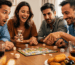 Cuatro amigos jugando a un juego de mesa de sobremesa con tablero, fichas y dados en una mesa con aperitivos