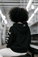 Mujer de espaldas con sudadera negra unisex CLAVAO de Zasca in Games mostrando logo trasero