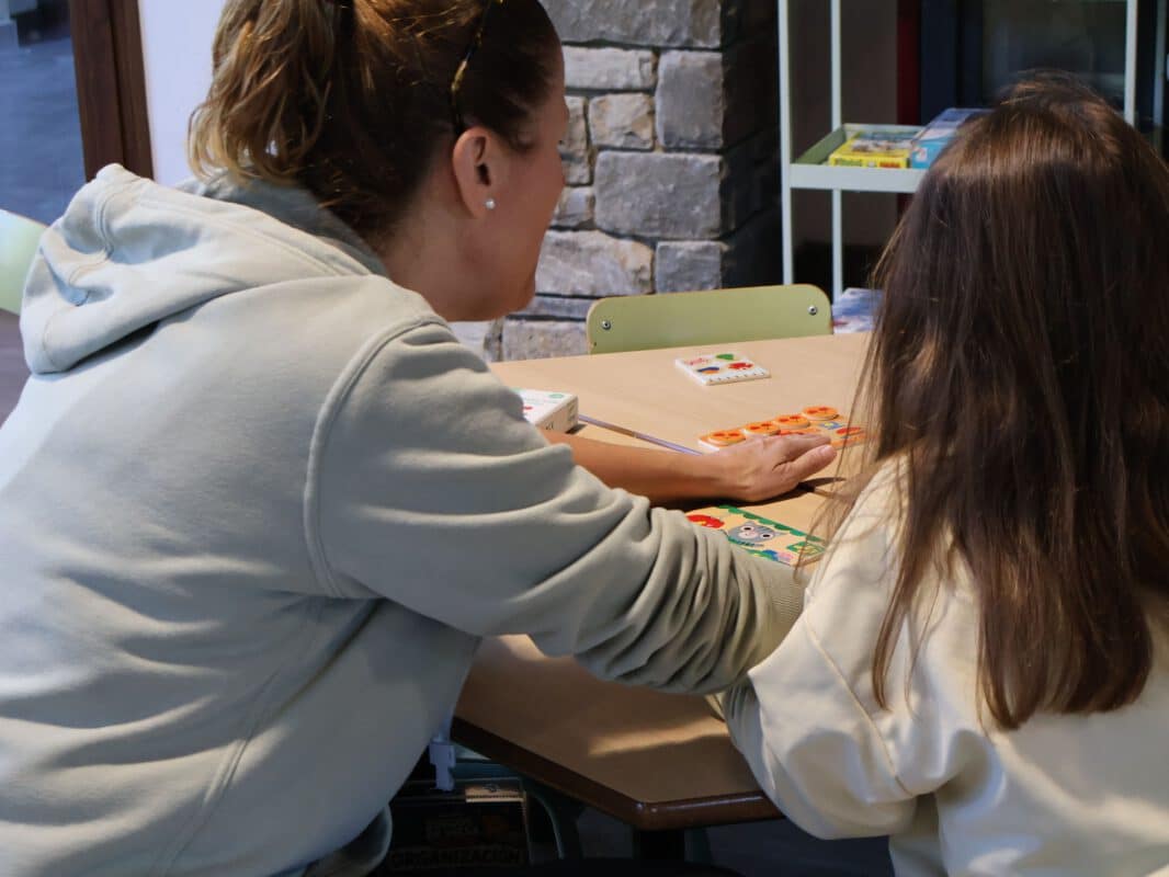 Adulta y niña jugando juntas a un juego de mesa durante unas jornadas familiares